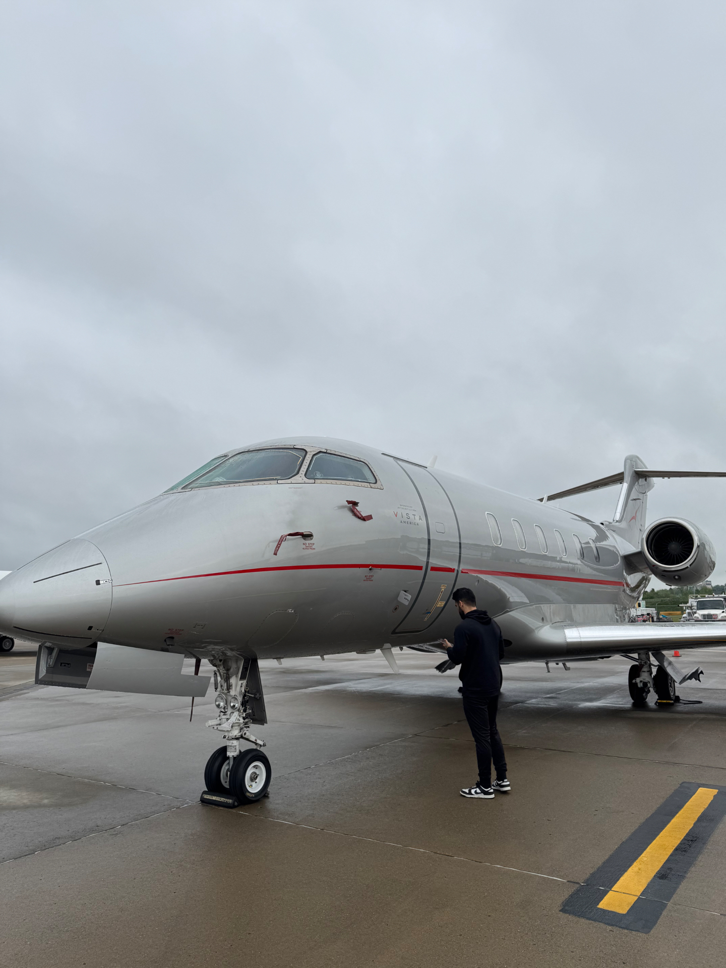 Professional aircraft exterior cleaning service — technician washing and polishing private jet fuselage on airport tarmac